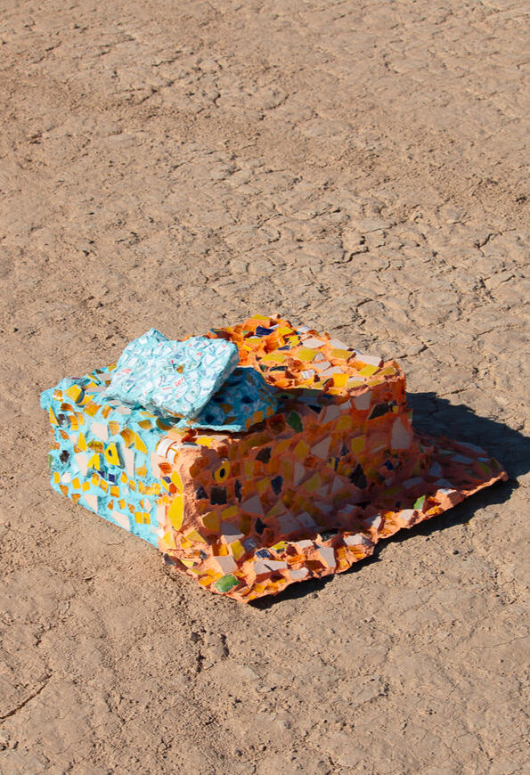 Still from durational performance by Adriana Chavez. Features Adriana dressed as her character Juan Chico hammering in cardboard sign that says "claimed" on it in black letters.
