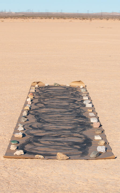 Image of sculpture by D.K. Sole. Features numerous bottle caps wrapped in tin foil placed on ground huddled together.