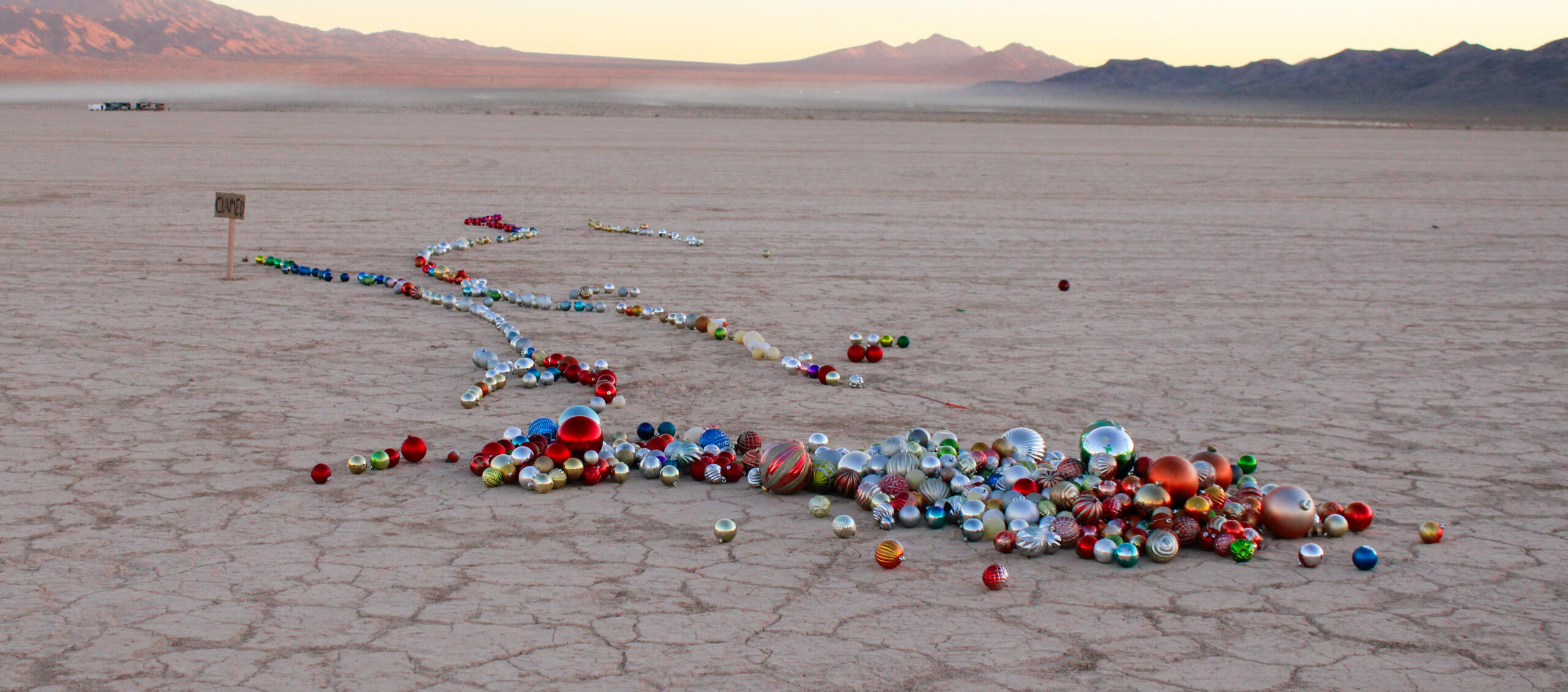 Image of sculpture by Alisha Kerlin. Features numerous Christmas decorations of various sizes tied together and to an anchor point on the lake-bed.